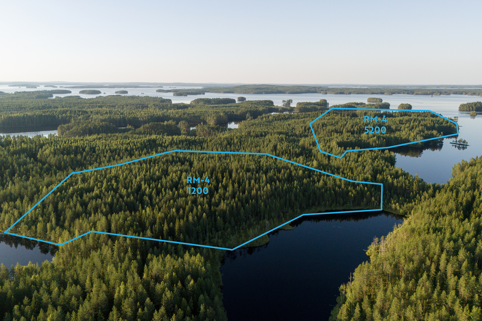 Ilmakuva alueesta ja yleiskaavan RM-4 kortteleista, metsää ja järveä.