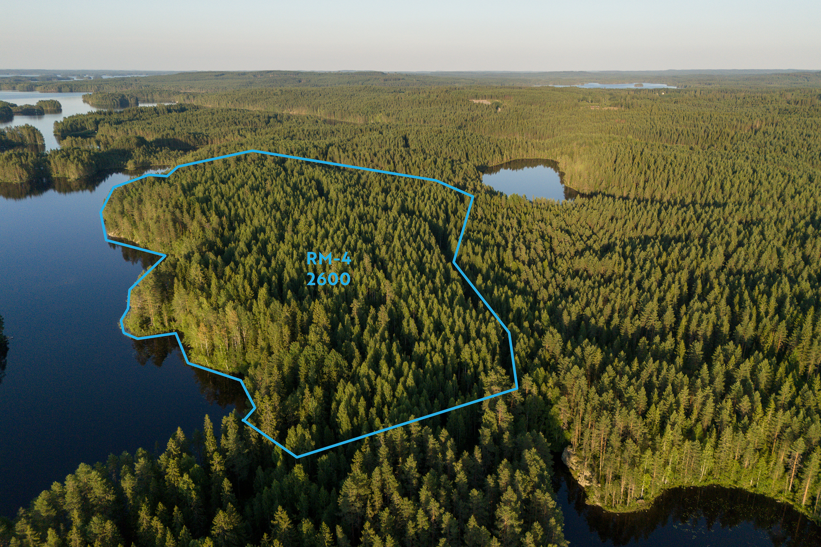 Ilmakuva alueesta ja yleiskaavan RM-4 kortteleista, metsää ja järveä.